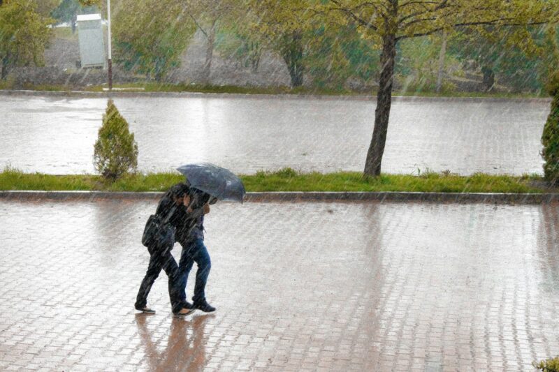 大雨の中傘をさして歩く人