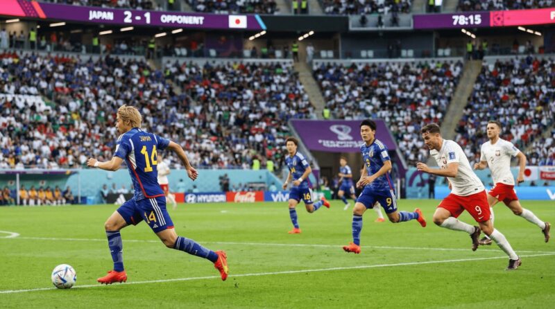 金髪の日本代表選手と周囲のプレーヤーがゴールを狙う画像