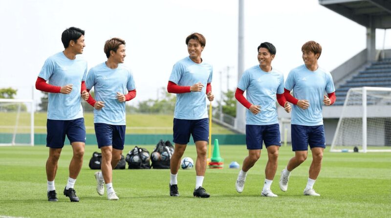 赤インナー付き水色練習着の日本人選手たちがジョギングする光景